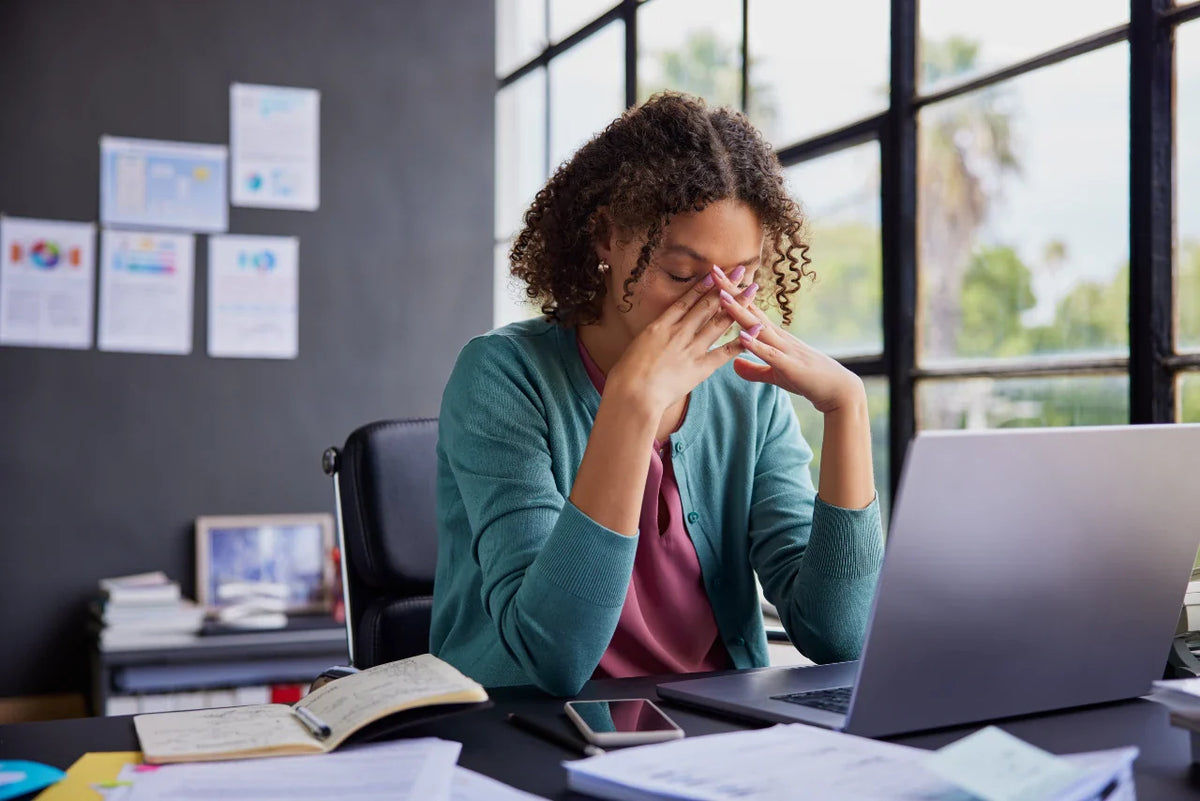Woman in an office with her head in her hands showing the midday slump